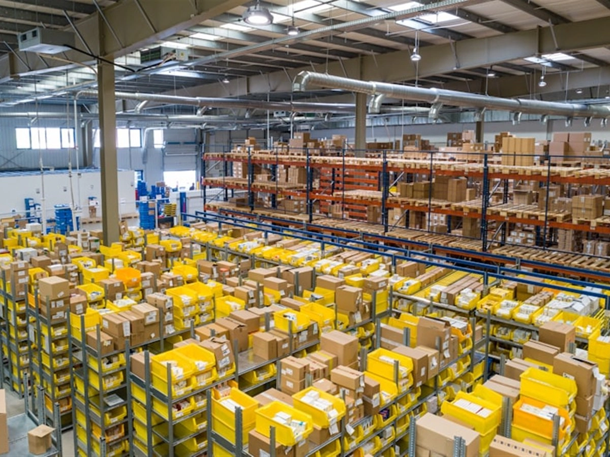 Magazijn met veel gele bakken en kartonnen dozen op stellingen