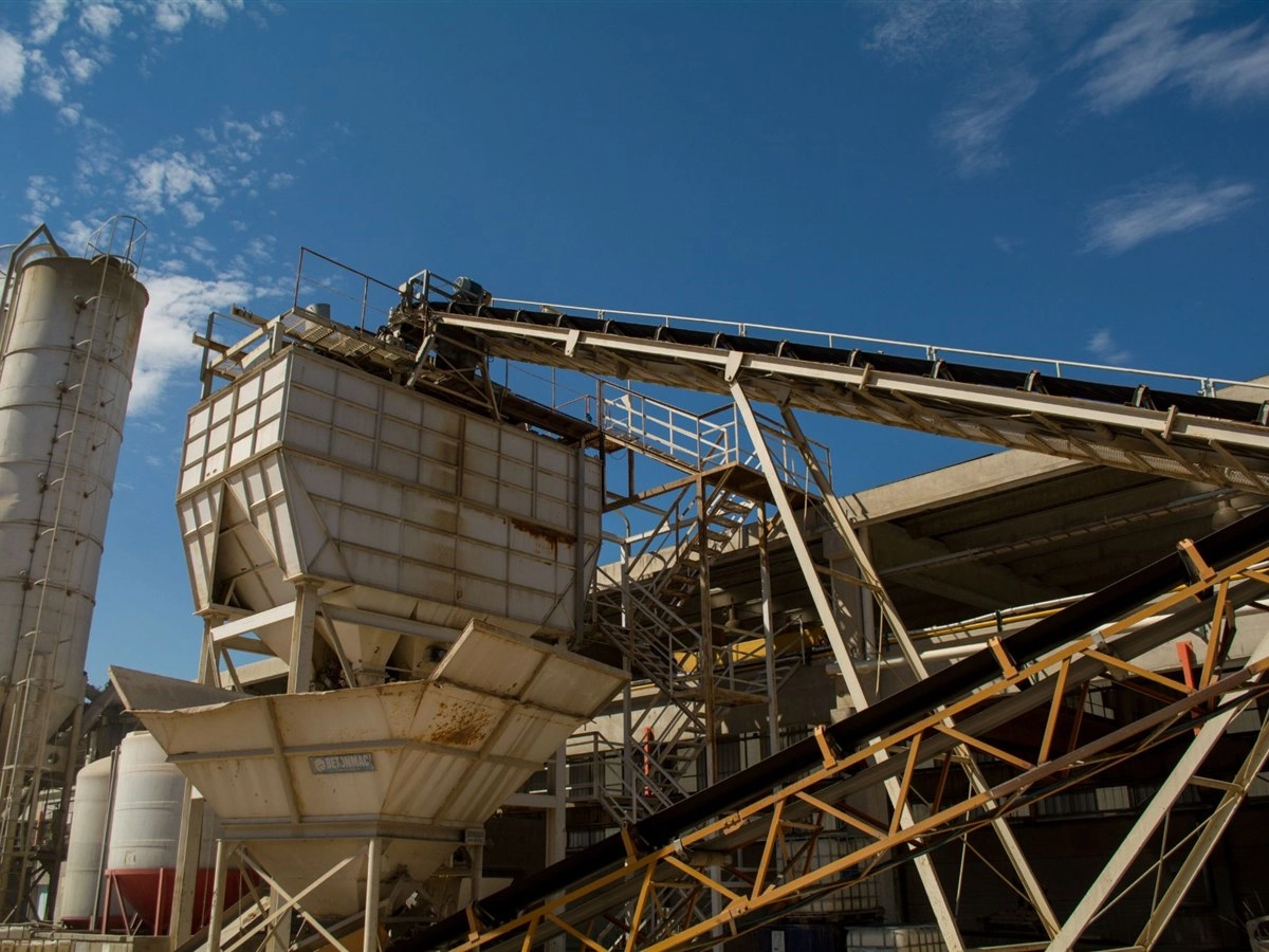 Betoncentrale met silo's, transportbanden en opslagbakken onder een blauwe lucht
